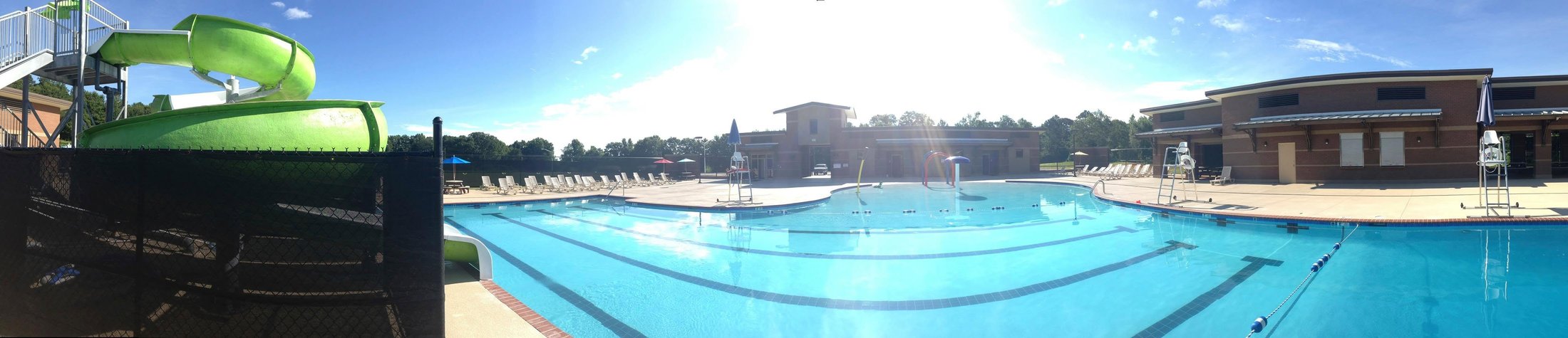 Panorama of the Piedmont Aquatic Center pool with a green water slide and bathhouse