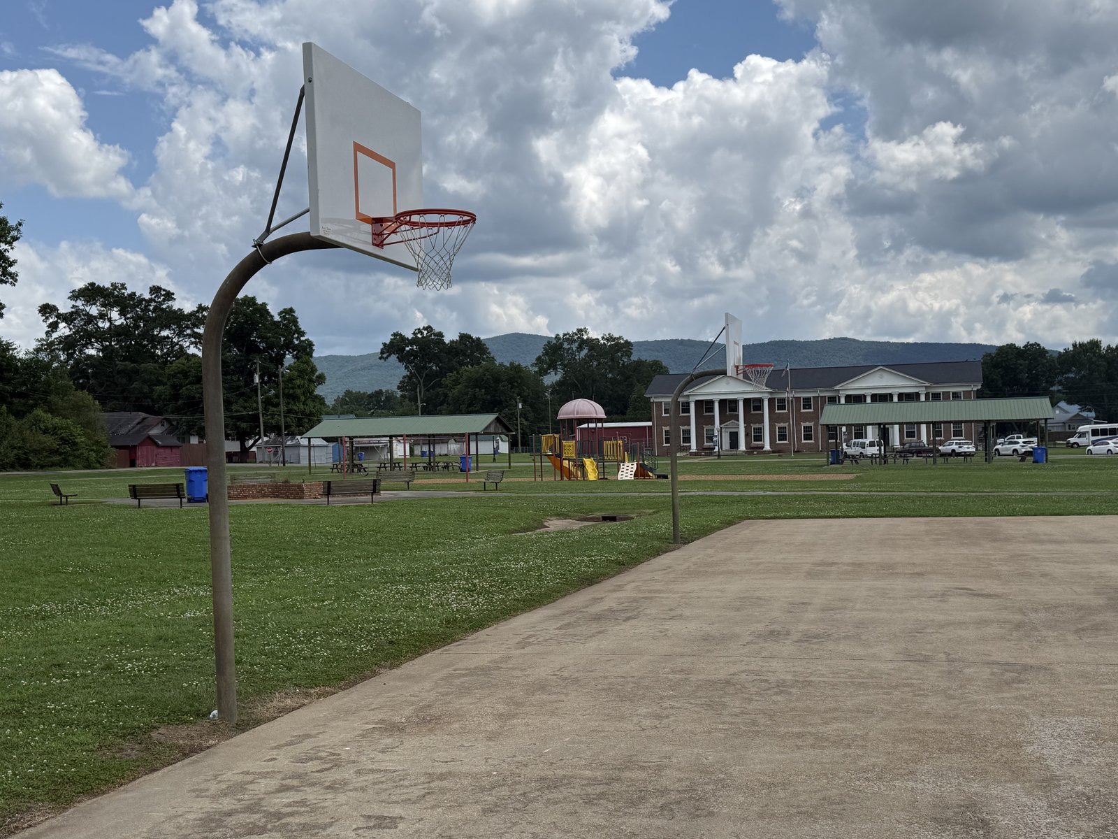 A basketball goal and open field at Fagan's Park with the mountains in the distance