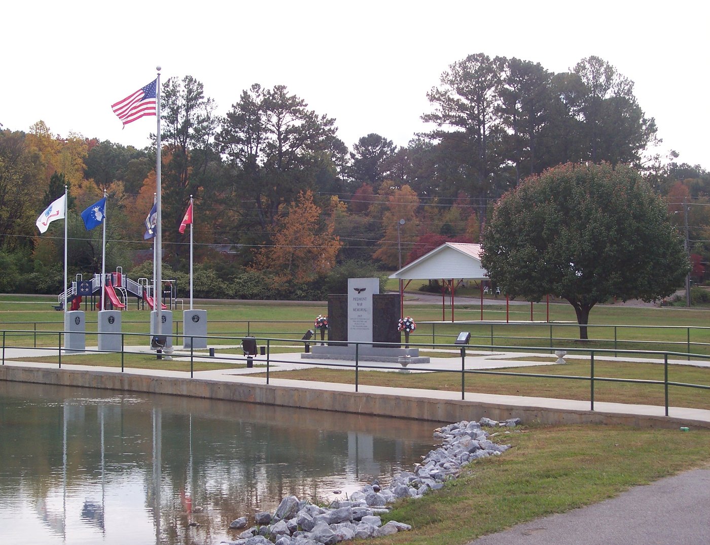 Veterans Memorial Park in Piedmont with flags, a memorial, and a pond